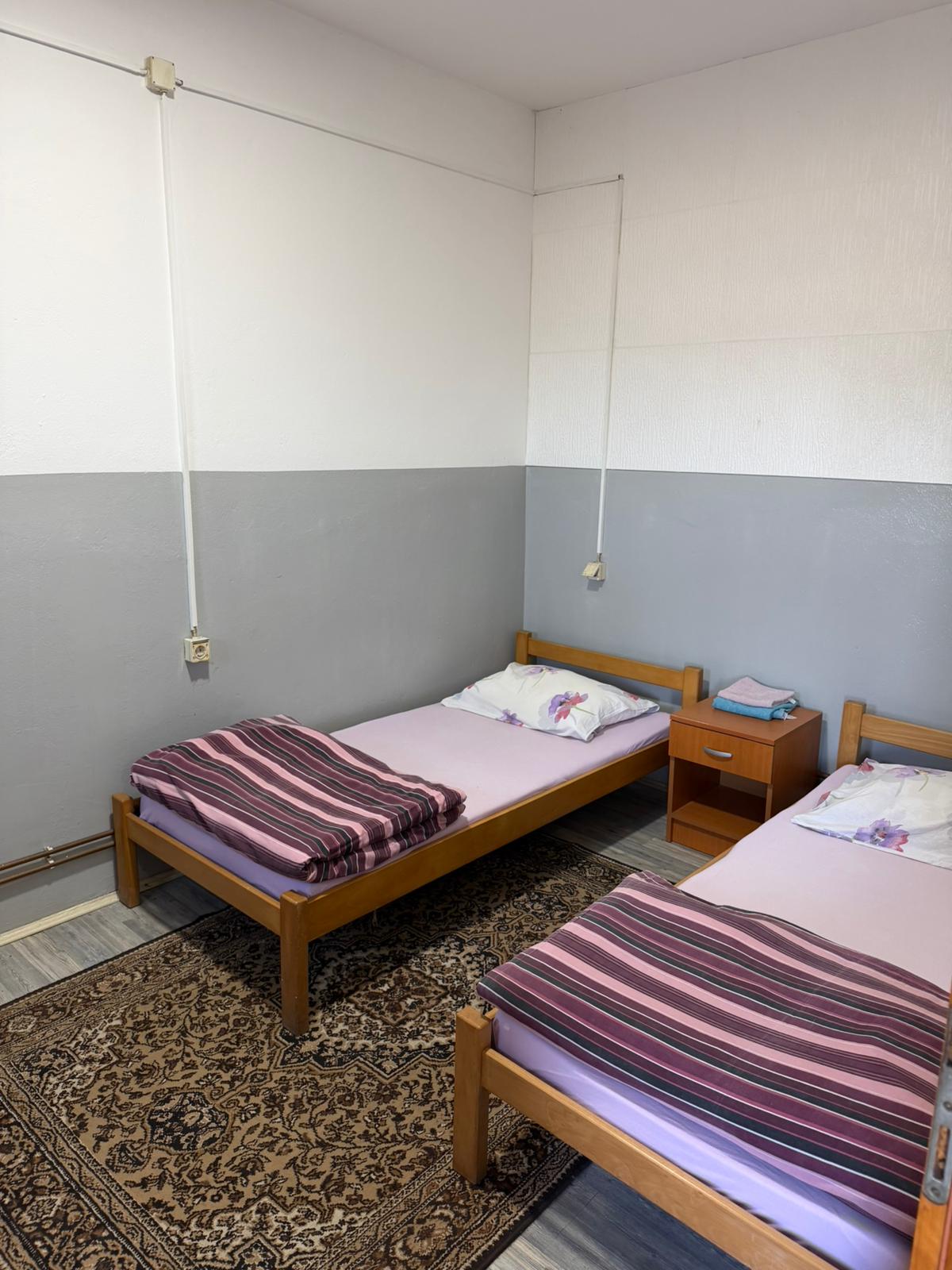 Soba sa dva kreveta i sivim zidom